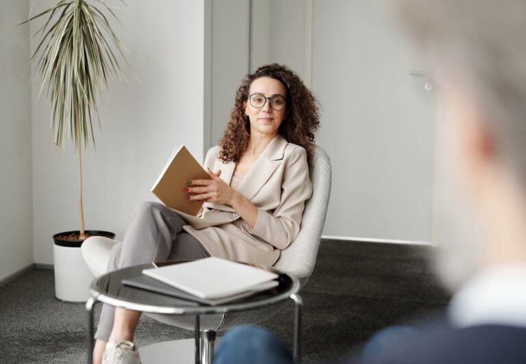 Woman reading a book while sitting in a modern chair indoors.