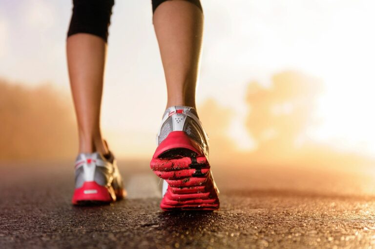 Close-up of a person walking or running on a paved road at sunrise or sunset.