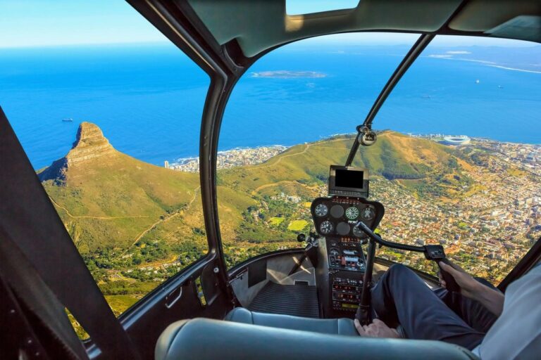 View from a helicopter cockpit flying over coastal hills and the ocean.