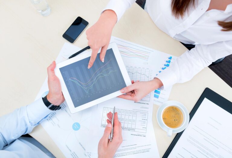 Two professionals reviewing data on a tablet during a meeting.